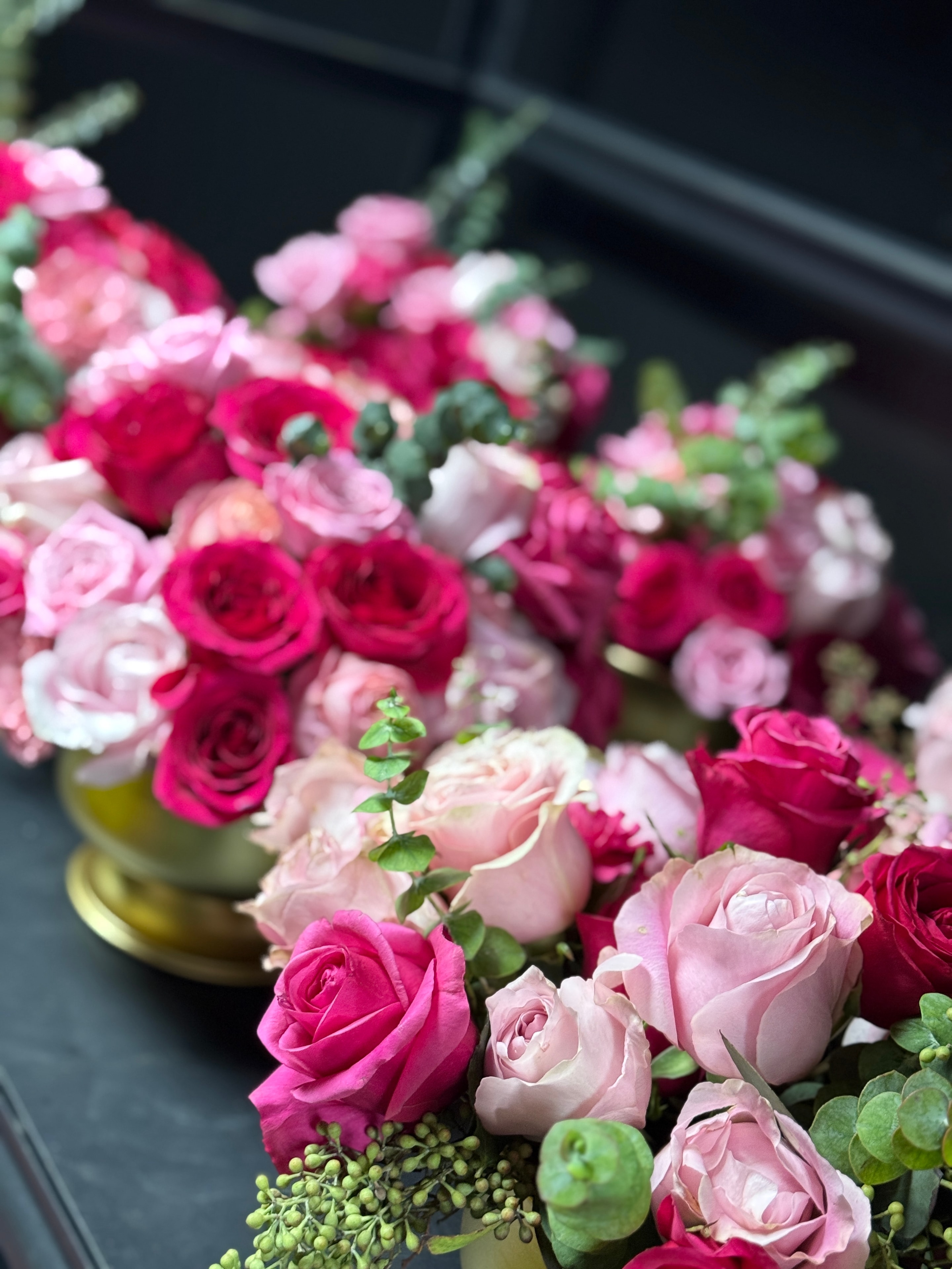 Quinceañera centerpieces with hot pink and blush roses in gold vases with eucalyptus greenery