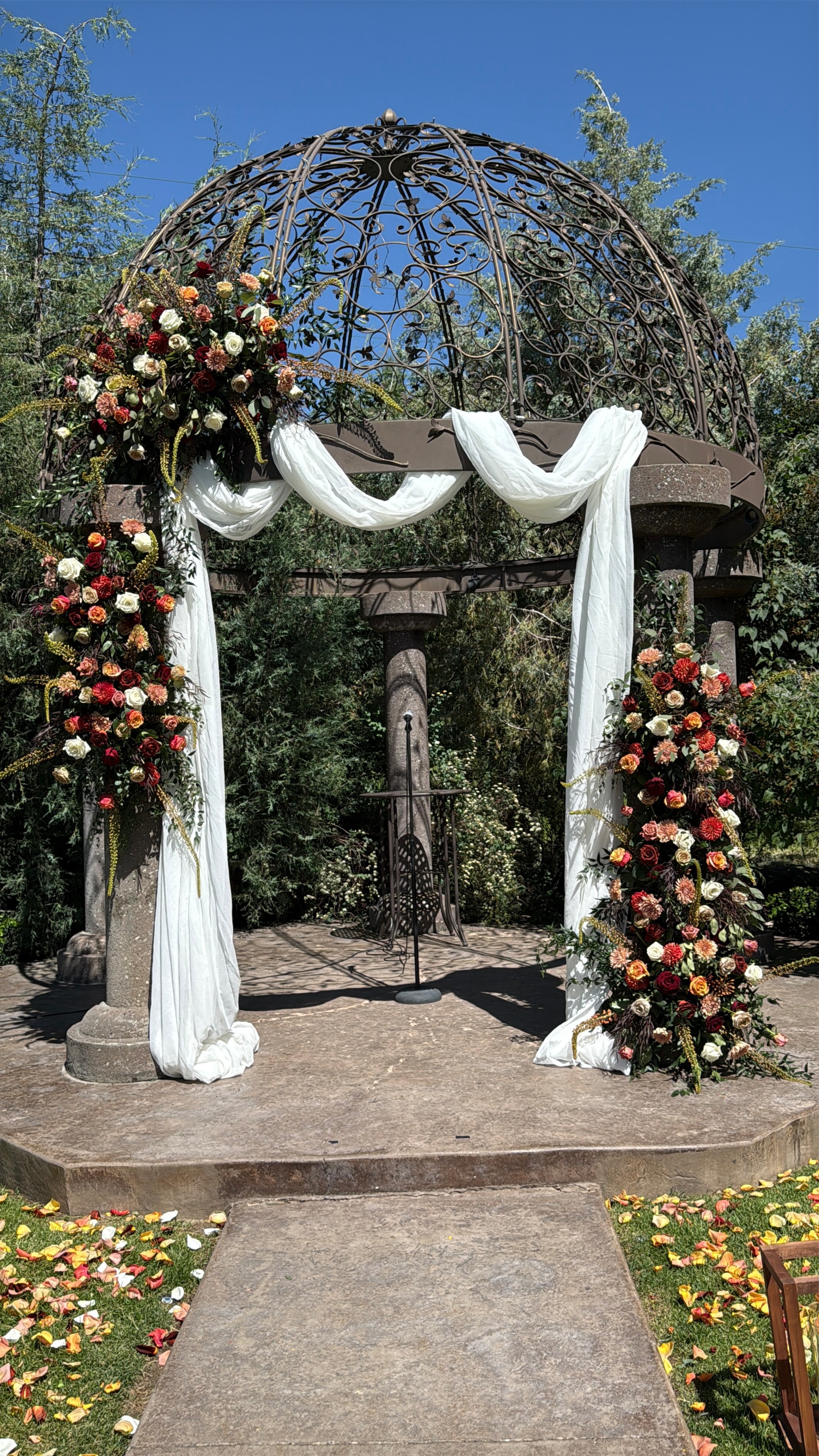 Bride standing next to ornate floral installation by water fountain