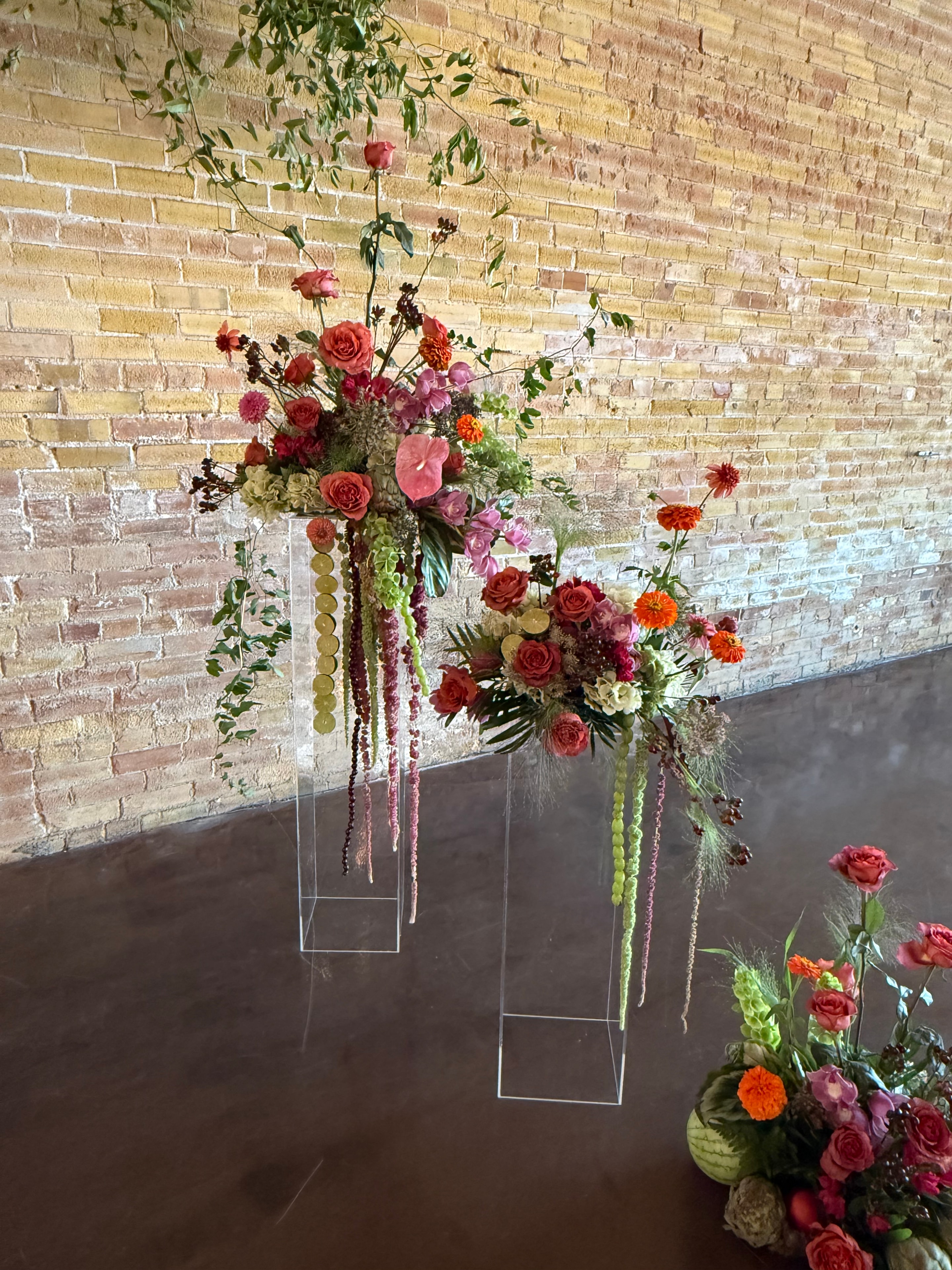 Overhead view of floral arrangements on acrylic pedestals on brick floor